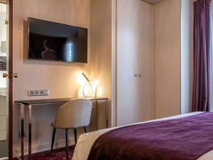 a bedroom with a bed and a desk with a chair at Mercure Paris Place d'Italie in Paris