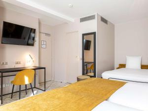 a hotel room with two beds and a desk and a tv at Mercure Paris Place d'Italie in Paris