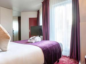 a bedroom with a large bed with purple sheets and a window at Mercure Paris Place d'Italie in Paris