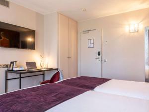 a hotel room with a bed and a desk with a laptop at Mercure Paris Place d'Italie in Paris