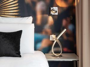 a bedroom with a bed and a lamp on a night stand at Mercure Paris Place d'Italie in Paris