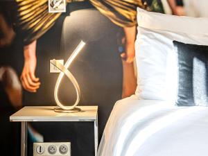 a lamp on a night stand next to a bed at Mercure Paris Place d'Italie in Paris