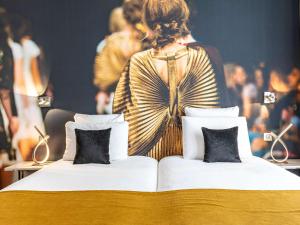 a bed with two pillows in front of a crowd at Mercure Paris Place d'Italie in Paris