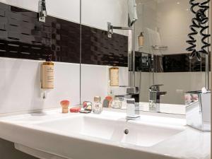 a bathroom with a white sink and a mirror at Mercure Paris Place d'Italie in Paris