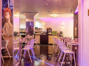 a restaurant with purple lighting and tables and chairs at Mercure Paris Place d'Italie in Paris