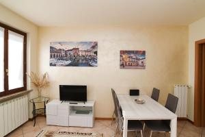 a dining room with a white table and a tv at Rovato entire apartment in the capital of Franciacorta in Rovato