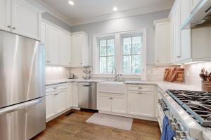 a kitchen with white cabinets and a stainless steel refrigerator at The Ocean Hideaway in Seabrook Island