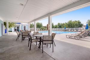a patio with a table and chairs and a pool at Millville By The Sea in Millville