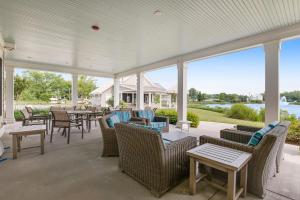 a covered porch with chairs and tables and a view of the water at Millville By The Sea in Millville