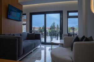 a living room with a couch and a tv and a table at Alkyonis Hotel & Spa in Kato Loutraki