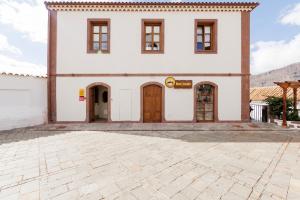 un gran edificio blanco con puertas marrones y un patio en LOFT 360º VIEW - La Casa de la Esquina, en Tejeda