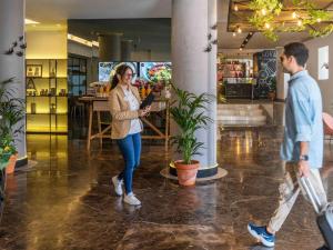 a woman standing in a lobby with a man at Mercure Porto Centro Santa Catarina in Porto