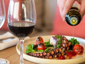 a person is pouring wine into a plate of food at Mercure Porto Centro Santa Catarina in Porto