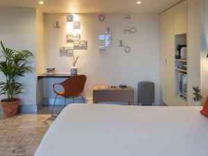 a room with a bed and a table and chairs at Mercure Porto Centro Santa Catarina in Porto