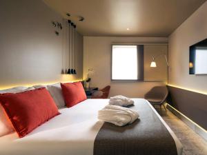 a bedroom with a large bed with red pillows at Mercure Porto Centro Santa Catarina in Porto