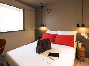 a bedroom with a white bed with red pillows at Mercure Porto Centro Santa Catarina in Porto