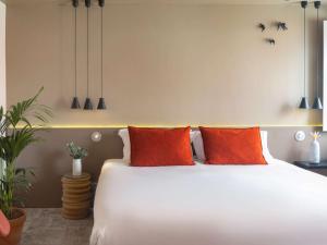 a bedroom with a white bed with orange pillows at Mercure Porto Centro Santa Catarina in Porto