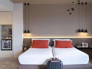 a bedroom with two beds and a suitcase at Mercure Porto Centro Santa Catarina in Porto