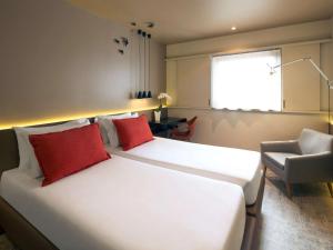 a bedroom with a large white bed with red pillows at Mercure Porto Centro Santa Catarina in Porto