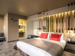 a bedroom with a large white bed with red pillows at Mercure Porto Centro Santa Catarina in Porto
