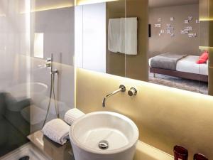 a bathroom with a white sink and a mirror at Mercure Porto Centro Santa Catarina in Porto