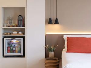 a bedroom with a refrigerator with drinks in it at Mercure Porto Centro Santa Catarina in Porto