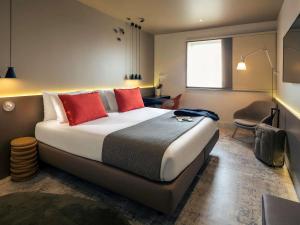 a hotel room with a large bed with red pillows at Mercure Porto Centro Santa Catarina in Porto