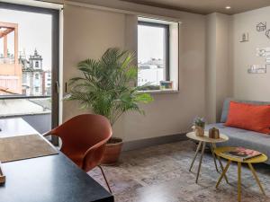 a living room with a couch and a plant at Mercure Porto Centro Santa Catarina in Porto