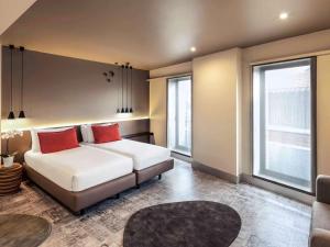 a bedroom with a bed with two red pillows at Mercure Porto Centro Santa Catarina in Porto