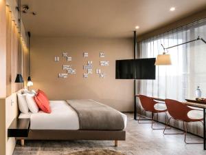 a bedroom with a bed and a table and chairs at Mercure Porto Centro Santa Catarina in Porto
