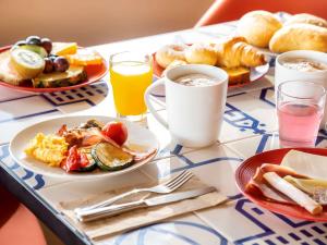 a table topped with plates of breakfast foods and drinks at Mercure Porto Centro Santa Catarina in Porto