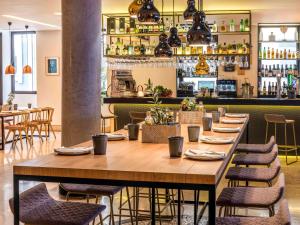 a long table in a restaurant with chairs and a bar at Mercure Porto Centro Santa Catarina in Porto