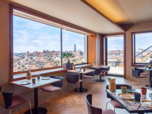 a restaurant with tables and chairs and large windows at Mercure Porto Centro Santa Catarina in Porto