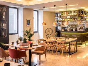 a restaurant with tables and chairs and a bar at Mercure Porto Centro Santa Catarina in Porto