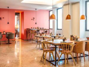 a restaurant with wooden tables and chairs and pink walls at Mercure Porto Centro Santa Catarina in Porto