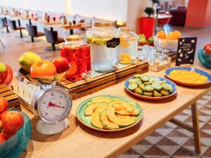 a table topped with plates of fruit and a clock at Mercure Porto Centro Santa Catarina in Porto