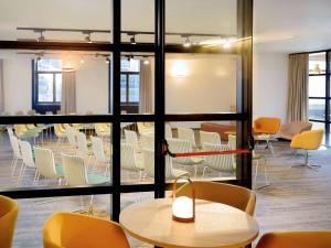 a room with chairs and tables and a room with windows at Mercure Porto Centro Santa Catarina in Porto