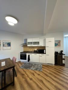 a kitchen with white cabinets and a wooden floor at Zeitperlewohnen Petrol in Witten