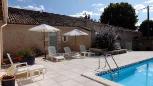 a patio with chairs and umbrellas and a pool at Maison Du Ruisseau in Malaville