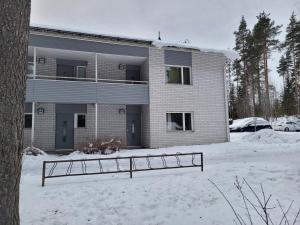 a building in the snow with a fence in front at Harjukatu in Äänekoski