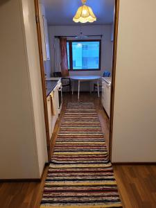 a hallway leading to a kitchen with a rug at Harjukatu in Äänekoski