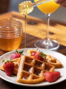a plate of waffles with strawberries and a drink at Tropikalya Prime Hotel in Balneário Camboriú