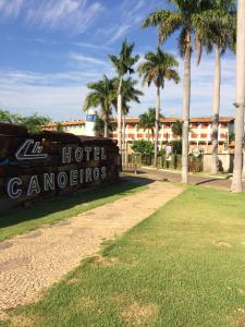 een bord voor een hotel met palmbomen bij Hotel Canoeiros in Pirapora