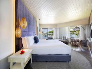 a bedroom with a large bed and a living room at Sofitel Fiji Resort & Spa in Denarau
