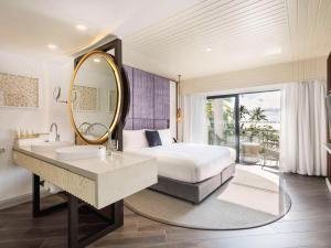 a bedroom with a bed and a mirror and a sink at Sofitel Fiji Resort & Spa in Denarau