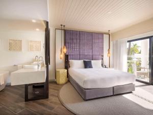a bedroom with a bed and a bathroom with a sink at Sofitel Fiji Resort & Spa in Denarau