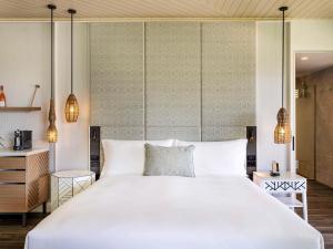 a bedroom with a large white bed and two lights at Sofitel Fiji Resort & Spa in Denarau