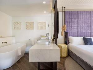 a bathroom with a tub and a bed and a sink at Sofitel Fiji Resort & Spa in Denarau