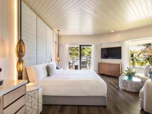 a bedroom with a large bed and a living room at Sofitel Fiji Resort & Spa in Denarau