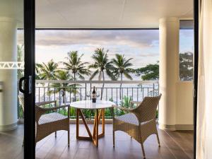 a balcony with a table and chairs and palm trees at Sofitel Fiji Resort & Spa in Denarau